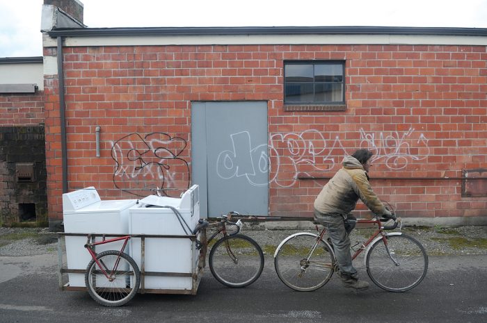 Vic Bonagofski hauls a makeshift bicycle trailer past a wall of graffiti in Centralia Tuesday.